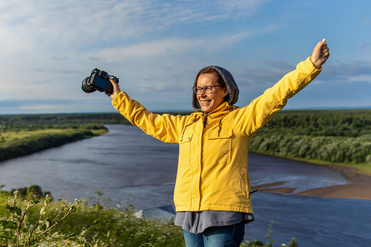 Happy adult woman in yellow jacket with camera. Female traveler photographer - Powered by Adobe