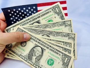 Notas de dolares em diversos valores com fundo branco e bandeira dos Estados Unidos da America.