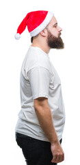 Young caucasian hipster man wearing christmas hat over isolated background looking to side, relax profile pose with natural face with confident smile.