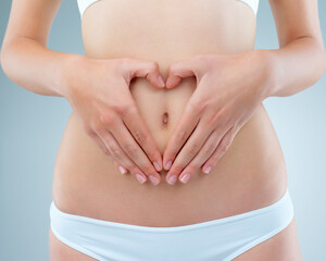 Woman, hands and stomach for nutrition in studio on white background with underwear. Female person, isolated and belly or waist with tummy tuck for self care with gut health, weight loss and wellness