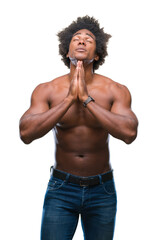 Fototapeta premium Afro american shirtless man showing nude body over isolated background begging and praying with hands together with hope expression on face very emotional and worried. Asking for forgiveness.
