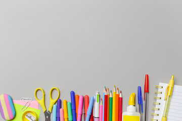 Back to school concept with variety of office and school supplies on grey background.