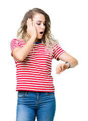 Beautiful young blonde woman over isolated background Looking at the watch time worried, afraid of getting late