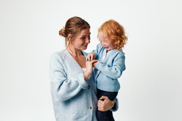 Mother and daughter embracing in blue sweater on white background, family love and connection concept