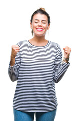 Young beautiful woman casual stripes sweater over isolated background excited for success with arms raised celebrating victory smiling. Winner concept.