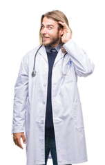 Young handsome doctor man with long hair over isolated background smiling with hand over ear listening an hearing to rumor or gossip. Deafness concept.