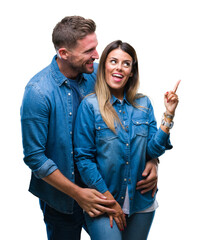 Young couple in love over isolated background with a big smile on face, pointing with hand and finger to the side looking at the camera.