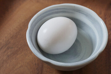 丸い陶器の小鉢に入っている卵