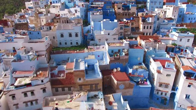 The picturesque photo showcases Chefchaouen, the Blue City in Morocco, famous for its vibrant azure buildings set against the enchanting mountain backdrop, creating a charming cityscape