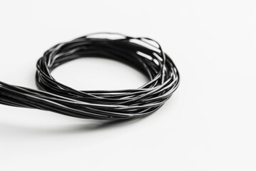 Coiled black electrical wire on a white background technology concept