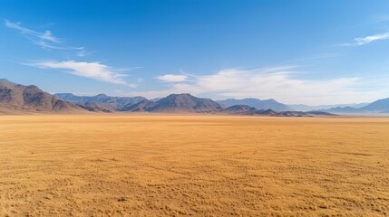 Fototapeta premium Expansive desert landscape with distant mountains under a clear blue sky, showcasing the beauty of untouched natural terrain.