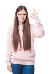 Young Chinese woman over isolated background wearing glasses smiling positive doing ok sign with hand and fingers. Successful expression.