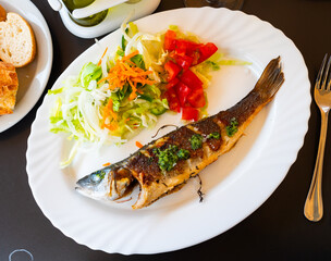 Fried baked whole carcass pike perch fish are complemented with salad of fresh vegetable carrot,...