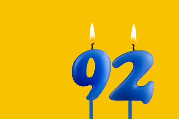 Blue birthday candle on yellow background - Number 92