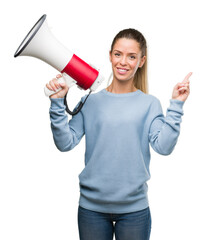 Beautiful young woman holding megaphone very happy pointing with hand and finger to the side