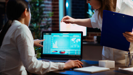 Manager and company financial advisor analyzing statistical graphs, zoom in shot on laptop screen. Management executive and worker comparing business revenue numbers in brick wall office, camera B