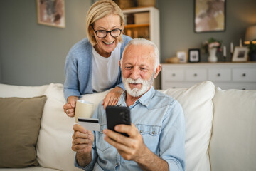 Senior couple buy online whit credit card on mobile phone at home