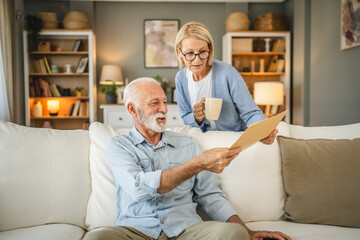 Senior couple receive a letter document from envelope together at home