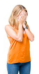 Beautiful young woman wearing orange shirt over isolated background with sad expression covering face with hands while crying. Depression concept.