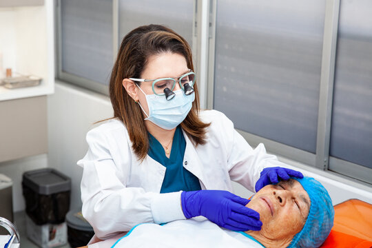 Dermatologist carrying out a skin biopsy on the face of a senior adult patient
