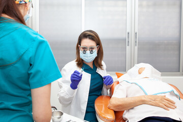 Dermatologist carrying out a skin biopsy on the face of a senior adult patient. Application of...