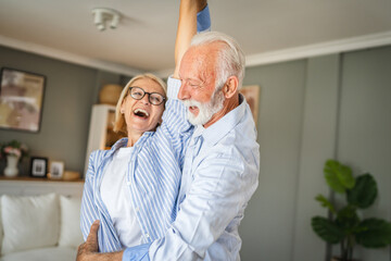 Fototapeta premium Senior active couple husband and wife dance and enjoy together at home