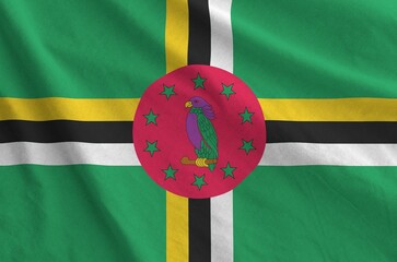 Dominica flag depicted on folded wavy fabric of old cloth close up