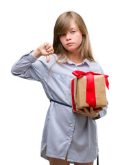 Young blonde toddler holding a present with angry face, negative sign showing dislike with thumbs down, rejection concept