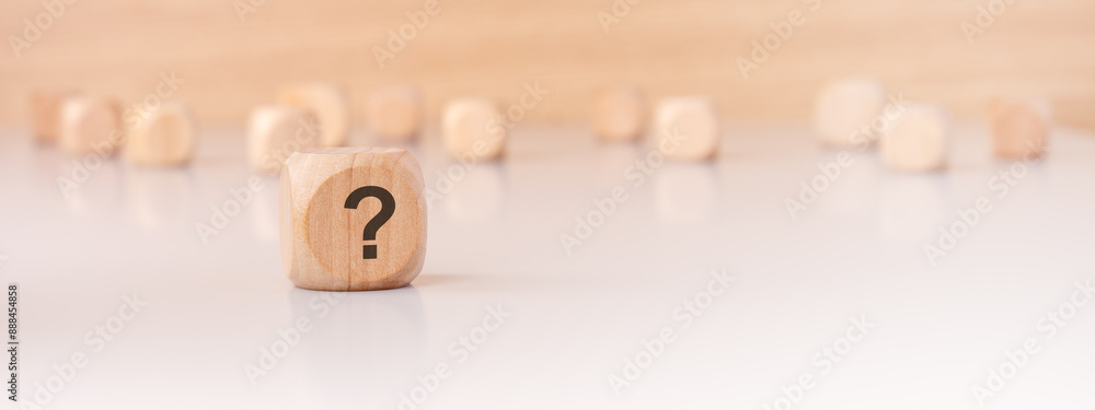 Poster a wooden block with a question mark written on it. many wooden cubes out of focus in the background