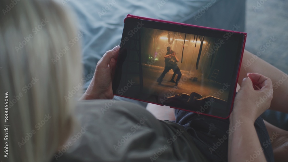 Poster close up of woman watching action movie using tablet computer while lying on sofa. caucasian woman r