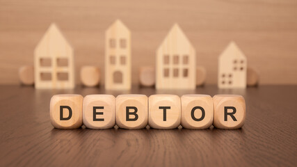wooden blocks spelling 'DEBTOR' with house cutouts, representing the intersection of law and real estate