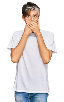Young hispanic man wearing casual white tshirt shocked covering mouth with hands for mistake. secret concept.