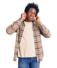 Handsome african american man with afro hair wearing casual clothes and glasses covering ears with...