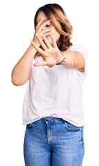 Young beautiful caucasian woman wearing casual white tshirt covering eyes with hands and doing stop gesture with sad and fear expression. embarrassed and negative concept.