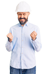 Young handsome man wearing architect hardhat excited for success with arms raised and eyes closed celebrating victory smiling. winner concept.