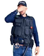 Young handsome man wearing police uniform covering eyes with hand, looking serious and sad. sightless, hiding and rejection concept