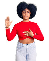 Young african american girl wearing casual clothes and glasses swearing with hand on chest and open...