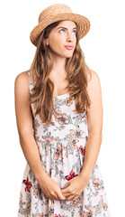 Beautiful caucasian young woman wearing summer hat smiling looking to the side and staring away thinking.