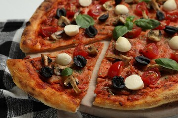 Tasty pizza with mozzarella, basil, tomatoes and olives on table, closeup