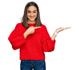 Beautiful brunette woman wearing casual winter sweater amazed and smiling to the camera while presenting with hand and pointing with finger.