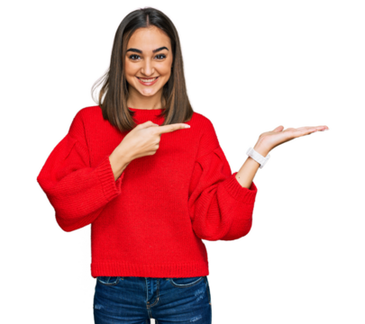 Beautiful brunette woman wearing casual winter sweater amazed and smiling to the camera while presenting with hand and pointing with finger.