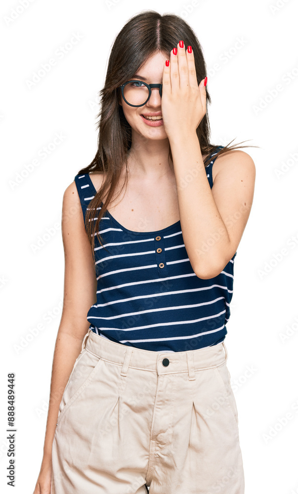 Poster young beautiful caucasian girl wearing casual clothes and glasses covering one eye with hand, confid