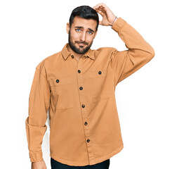 Young hispanic man wearing casual clothes confuse and wonder about question. uncertain with doubt, thinking with hand on head. pensive concept.