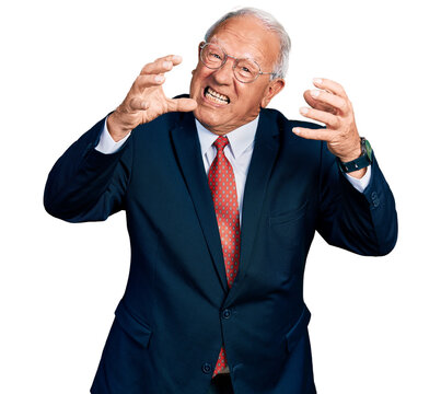 Senior man with grey hair wearing business suit and glasses shouting frustrated with rage, hands trying to strangle, yelling mad