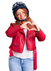 Young latin woman wearing leather jacket holding motorcycle helmet smiling in love showing heart symbol and shape with hands. romantic concept.