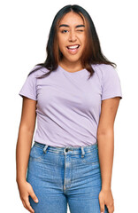 Obraz premium Young latin woman wearing casual clothes winking looking at the camera with sexy expression, cheerful and happy face.