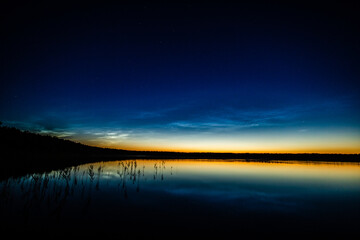 Lake at night, sky with stars, reflection in water, noctilucent clouds