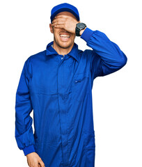 Bald man with beard wearing builder jumpsuit uniform smiling and laughing with hand on face covering eyes for surprise. blind concept.