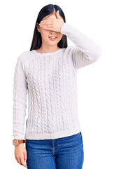 Fototapeta premium Young beautiful chinese woman wearing casual sweater smiling and laughing with hand on face covering eyes for surprise. blind concept.
