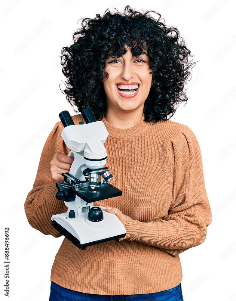 Poster Young middle east girl holding microscope smiling and laughing hard out loud because funny crazy joke.